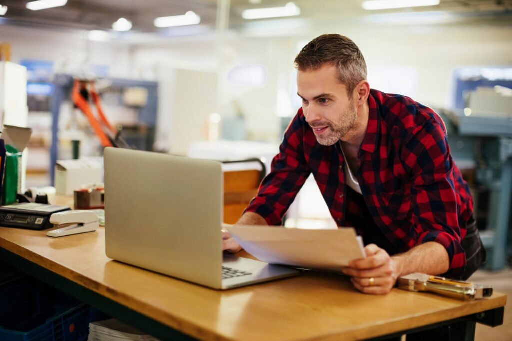 Homem em frente ao computador analisando notas em contingência off-line